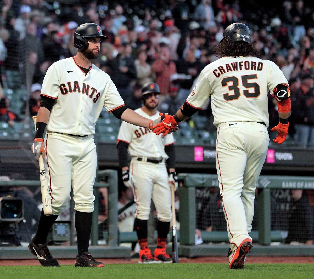 Brandon Belt (9) high fives Brandon Crawford (35) after he rounded the bases following his two-run homerun in the fifth inning as the San Francisco Giants played the Arizona Diamondbacks at Oracle Park in San Francisco, Calif., on Monday, June 14, 2021.