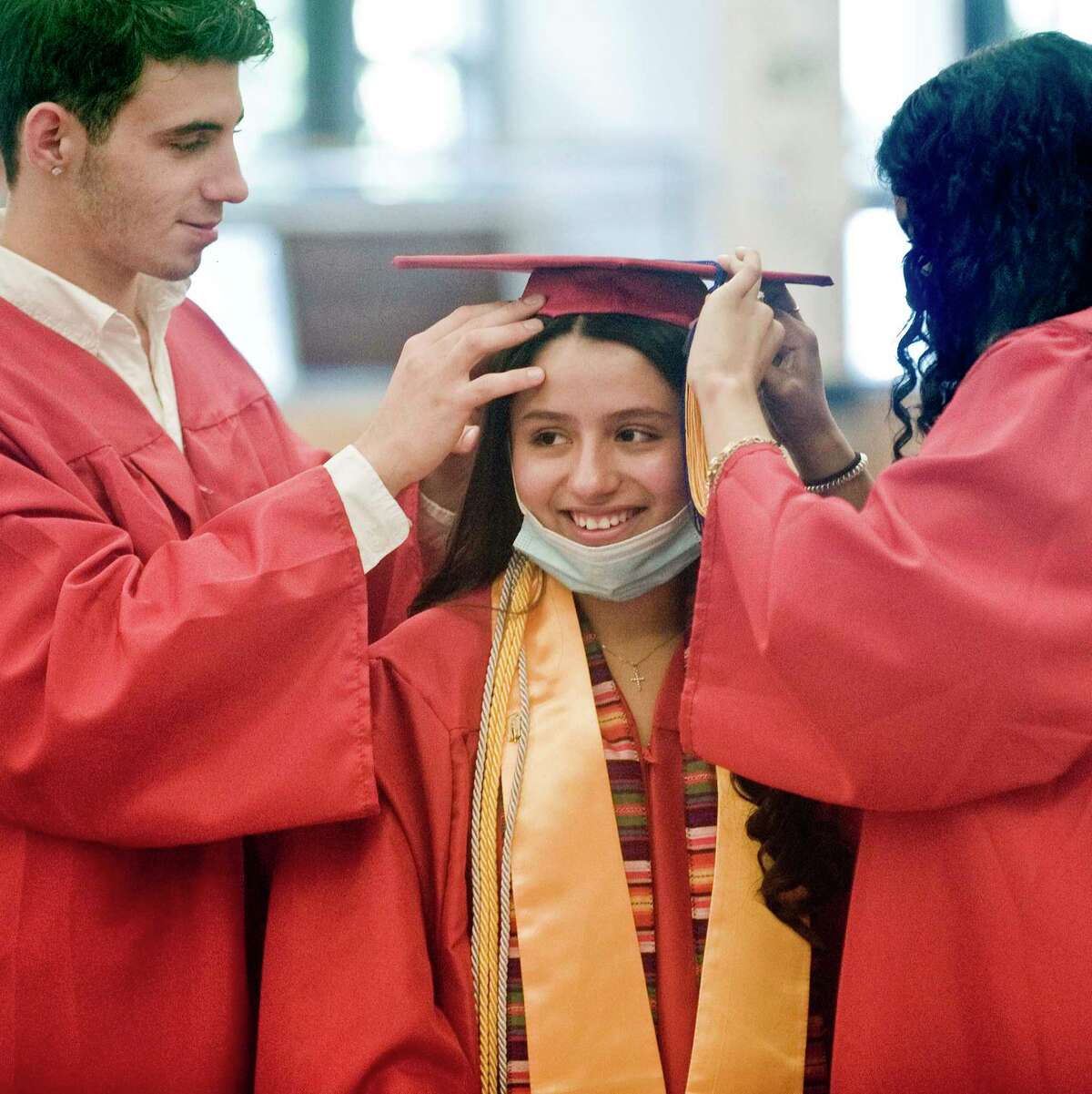 Lesly Vidal gets some hat help from Niholas Palumbo, left, and Kimberly Huertas, right, at the JM Wright Technical High School graduation. Monday, June 14, 2021