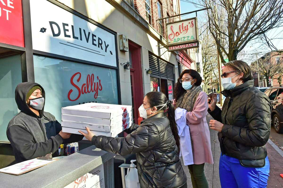 Ivan Parra, a Sally's Apizza employee serves free takeout pizza to Yale New Haven Hospital employees nurse Alienne Salleroli, R.N. , Priscilla Steve and nurse Curri Bower, R.N.