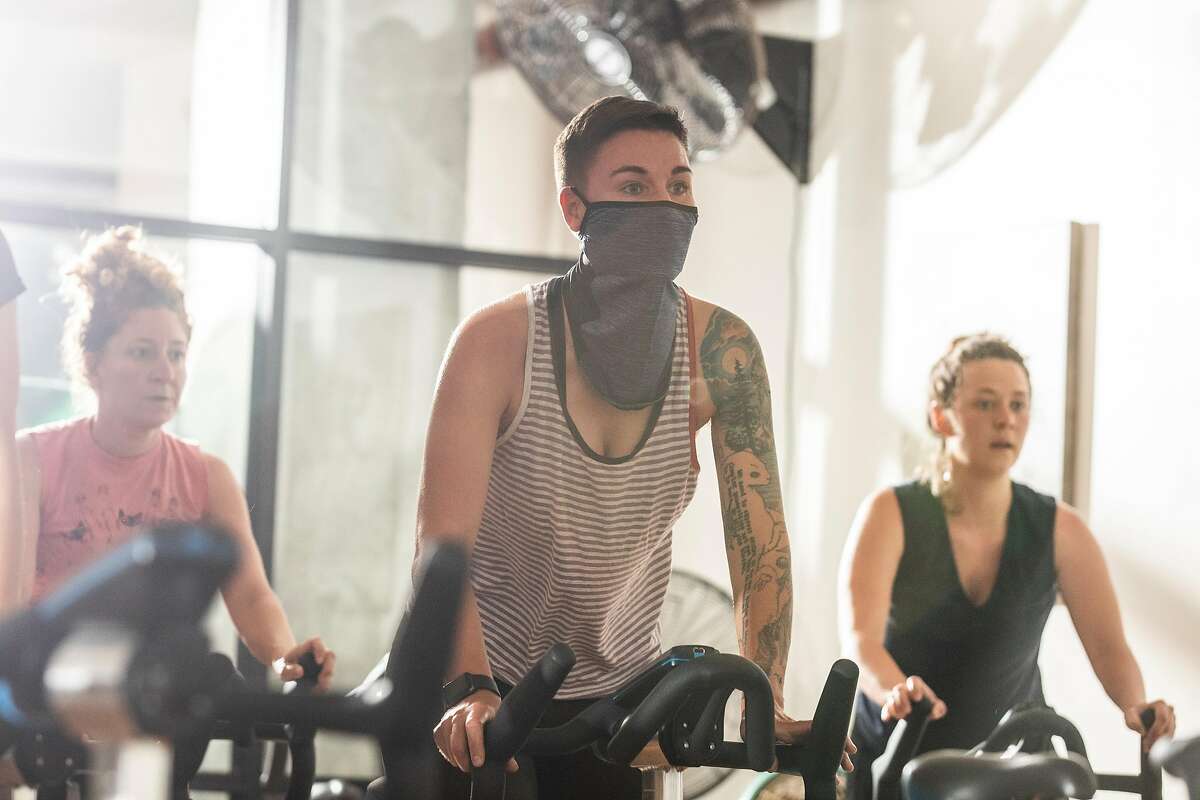 Tanya Wischerath wears a face covering at a cycle class at 17th Street Athletic Club in San Francisco on the day California reopens its economy. Mask wearing was optional for patrons of the studio.