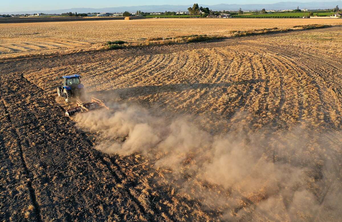 A tractor plows a dry field last month in Madera. Thousands of farms and water agencies that rely on flows from California’s vast delta watershed are being told to stop drawing water from rivers and creeks.