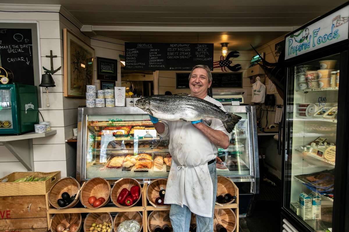 Scott Bennette, general manager of Rowayton Seafood Market in Norwalk, Conn., holds a fresh, whole salmon on June 2, 2021.
