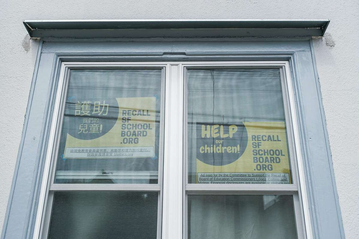 Posters promoting the recall of three members of the school board hang in the window of Kit Lam’s home in San Francisco.