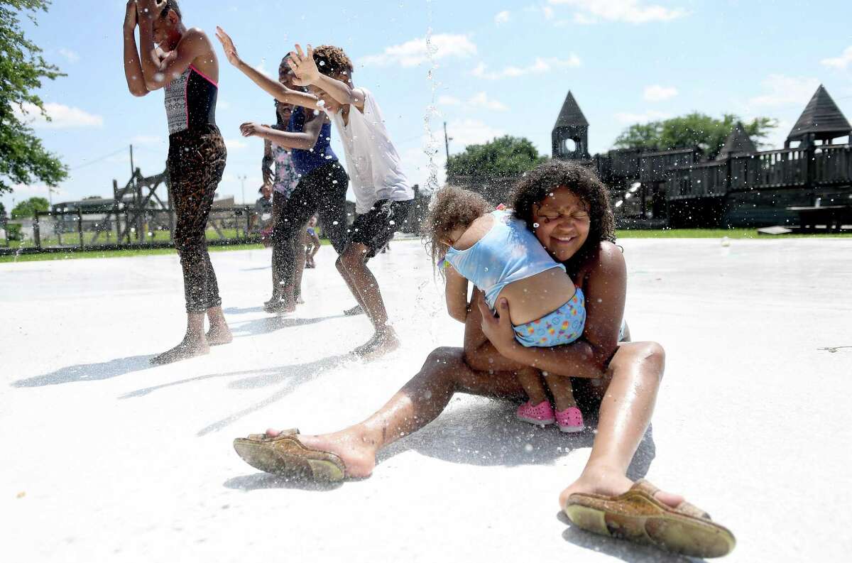 Stella St. Andre hugs young friend Aria Carrington as they enjoy the splash pad in Central Park as they try to beat another brutal day of heat Monday. Photo made Monday, June 14, 2021 Kim Brent/The Enterprise