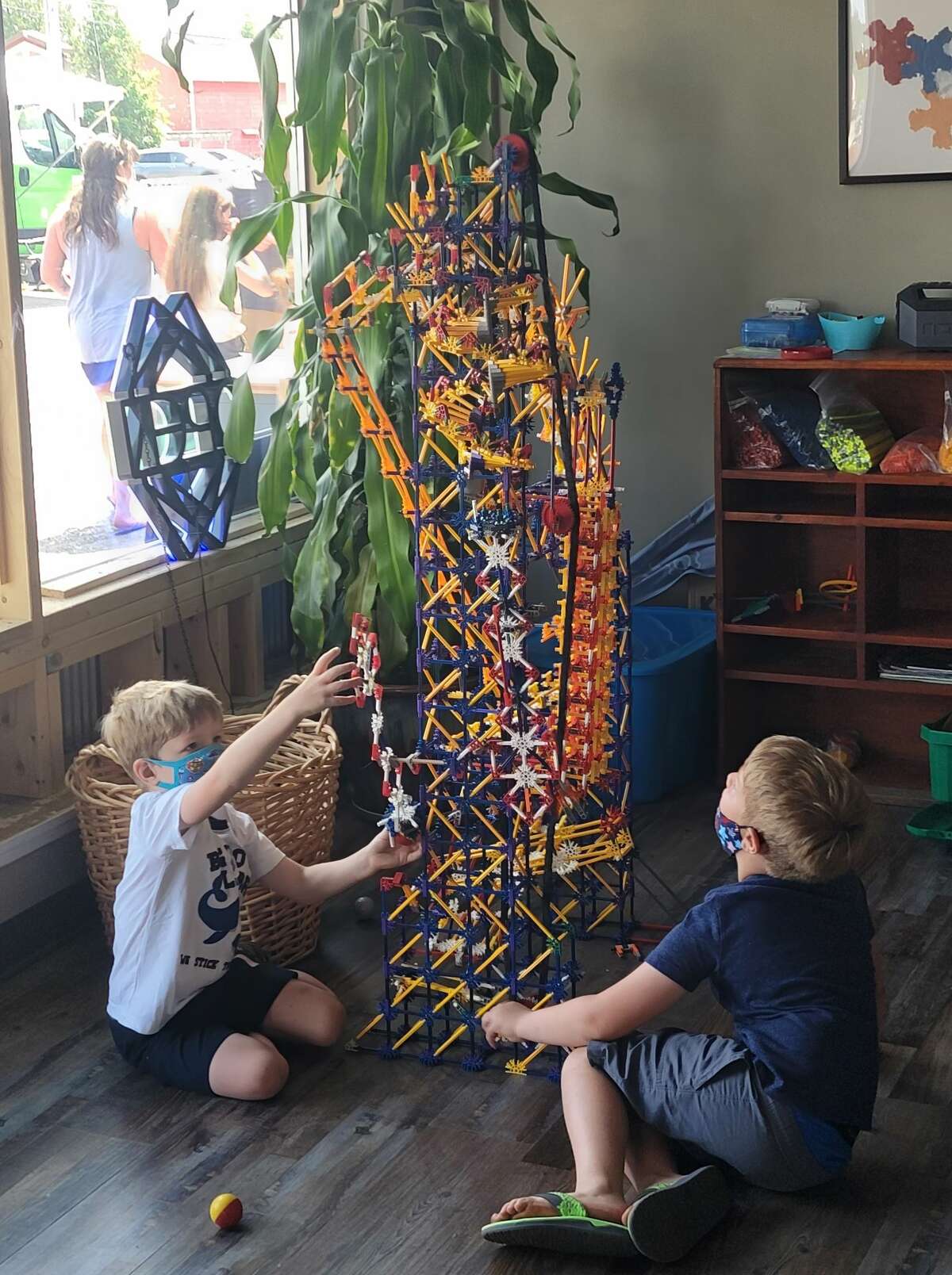 Children work on building a tower with an erector set type of building toy. 