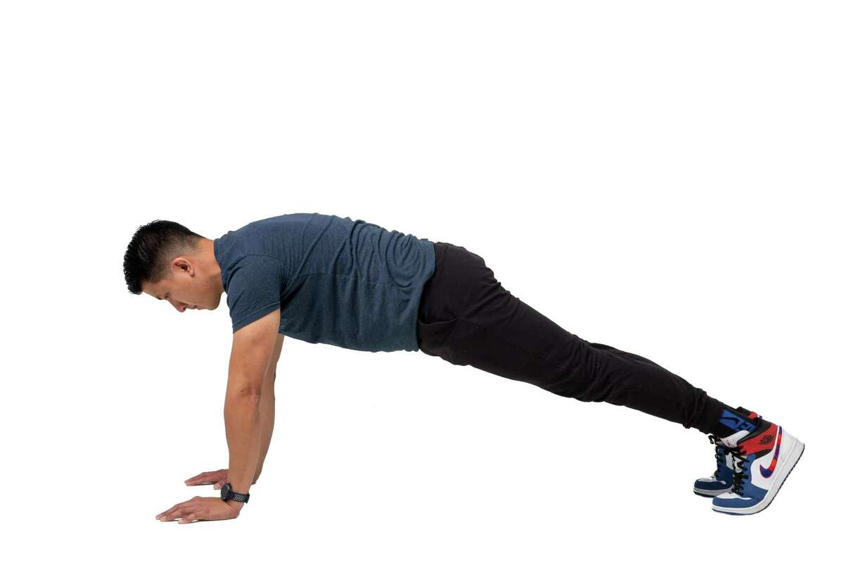Start in a plank position with your hands on the ground directly beneath your shoulders and the weight evenly distributed between your hands and toes