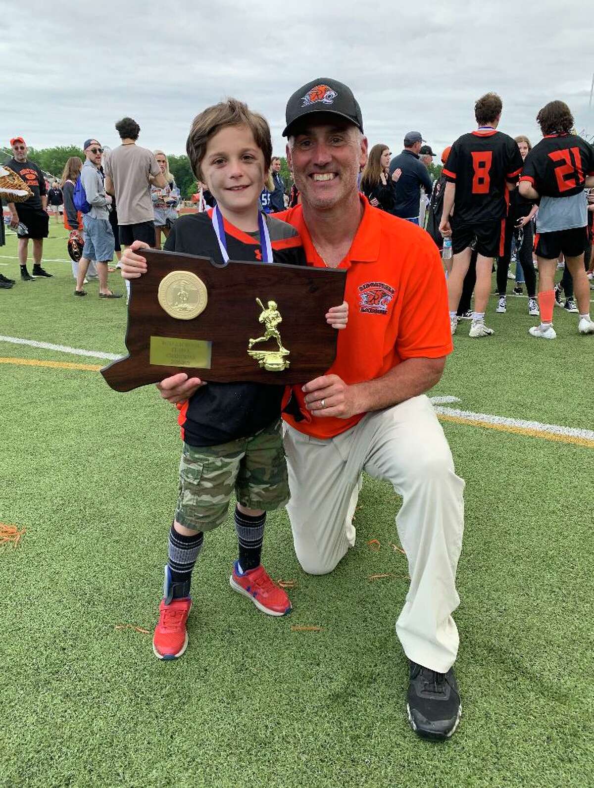 Conner Curran holds the state championship plaque alongside head lacrosse coach Roy Colsey.
