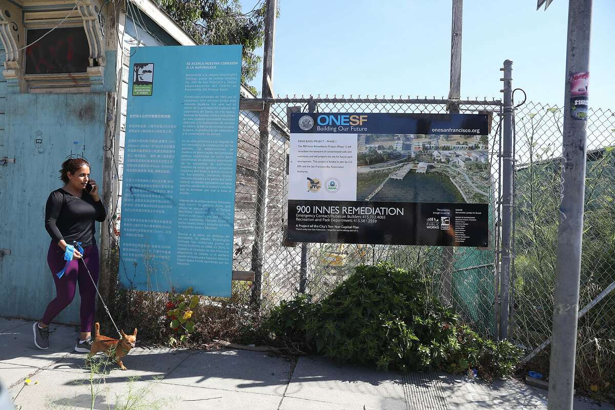A pedestrian walks past a sign about the 900 Innes Remediation Project while walking on Innes Street on Wednesday, June 16, 2021 in San Francisco, Calif.