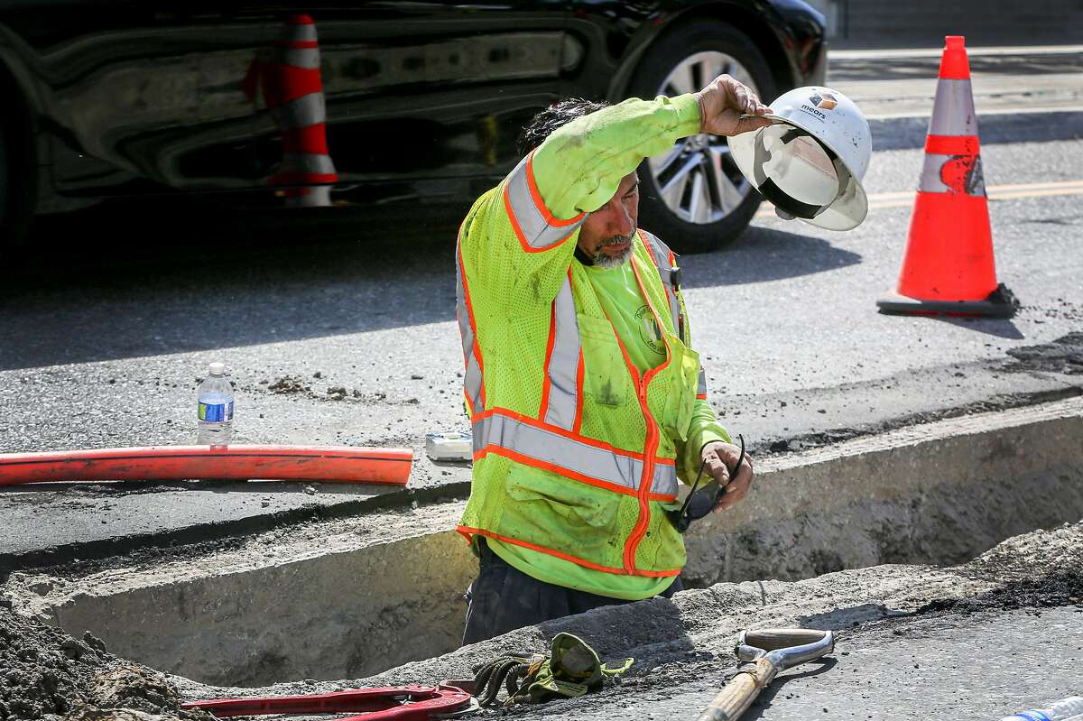 Luciano Salazar wipes sweat from his forehead while installing a telecommunication line on First Street toward downtown San Jose, Calif. on Wednesday, June 16, 2021. The National Weather Service is issuing heat warnings for most of the Bay Area and surrounding counties for the next several days.