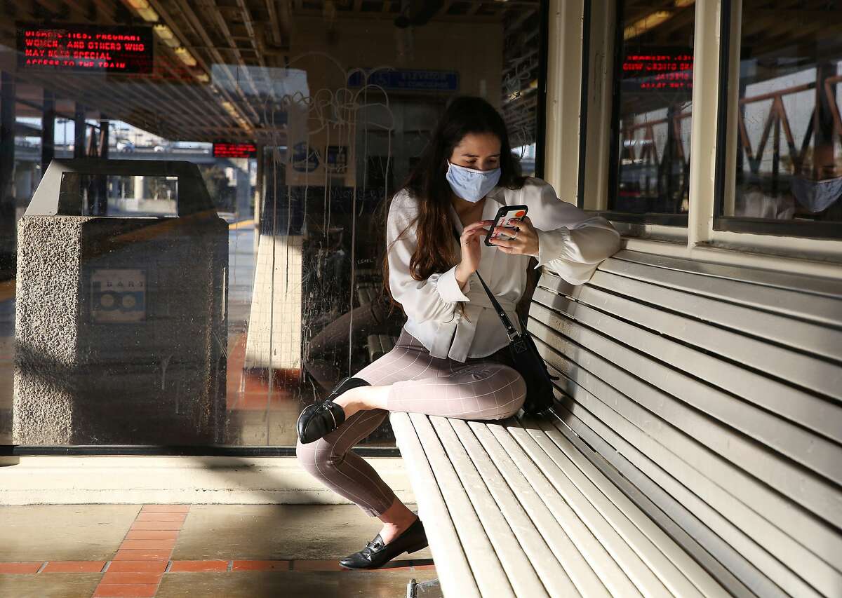 Emily Filkin wears a mask as she waits for the train toward San Francisco at MacArthur Station in Oakland on the day California lifted nearly all its pandemic restrictions on Tuesday, June 15, 2021.