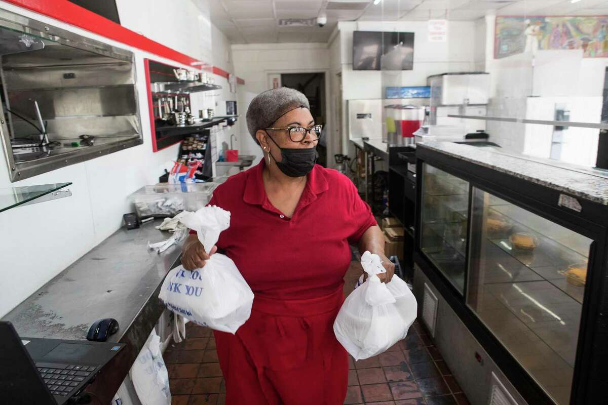 Mrs. Jerry Tillman carries a food order to a customer at Alfreda's Soul Food Tuesday, May 11, 2021 in Houston. Many small businesses didn't survive the pandemic, minority and women-owned businesses were particularlyhard hit. Despite the odds, Troy and Marguerite Williams' kept their restaurant, Alfreda's Soul Food, open.