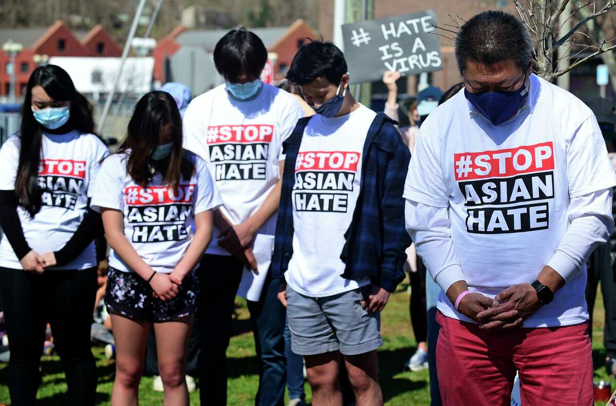 Over a hundred residents bow their heads with State Representative Tony Hwang they turned out to peacefully protest on Jesup Green Saturday, March 27, 2021, in Westport, Conn. The protesters gathered in solidarity with the AAPI community in opposition to the rise of hate crimes against that Asians and Pacific Islanders.