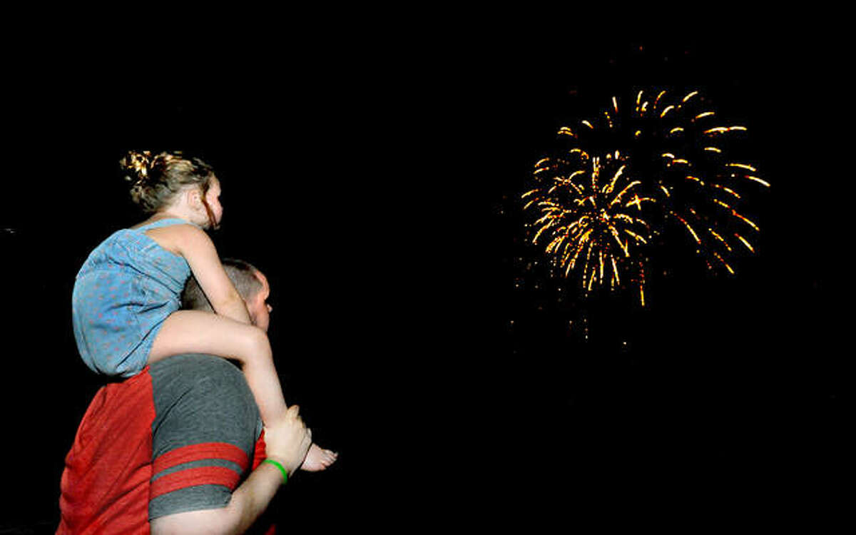 In this July 2020 file photo, Richard Miller and his daughter Zoey, 4, of Collinsville, watch fireworks at Edwardsville High School.