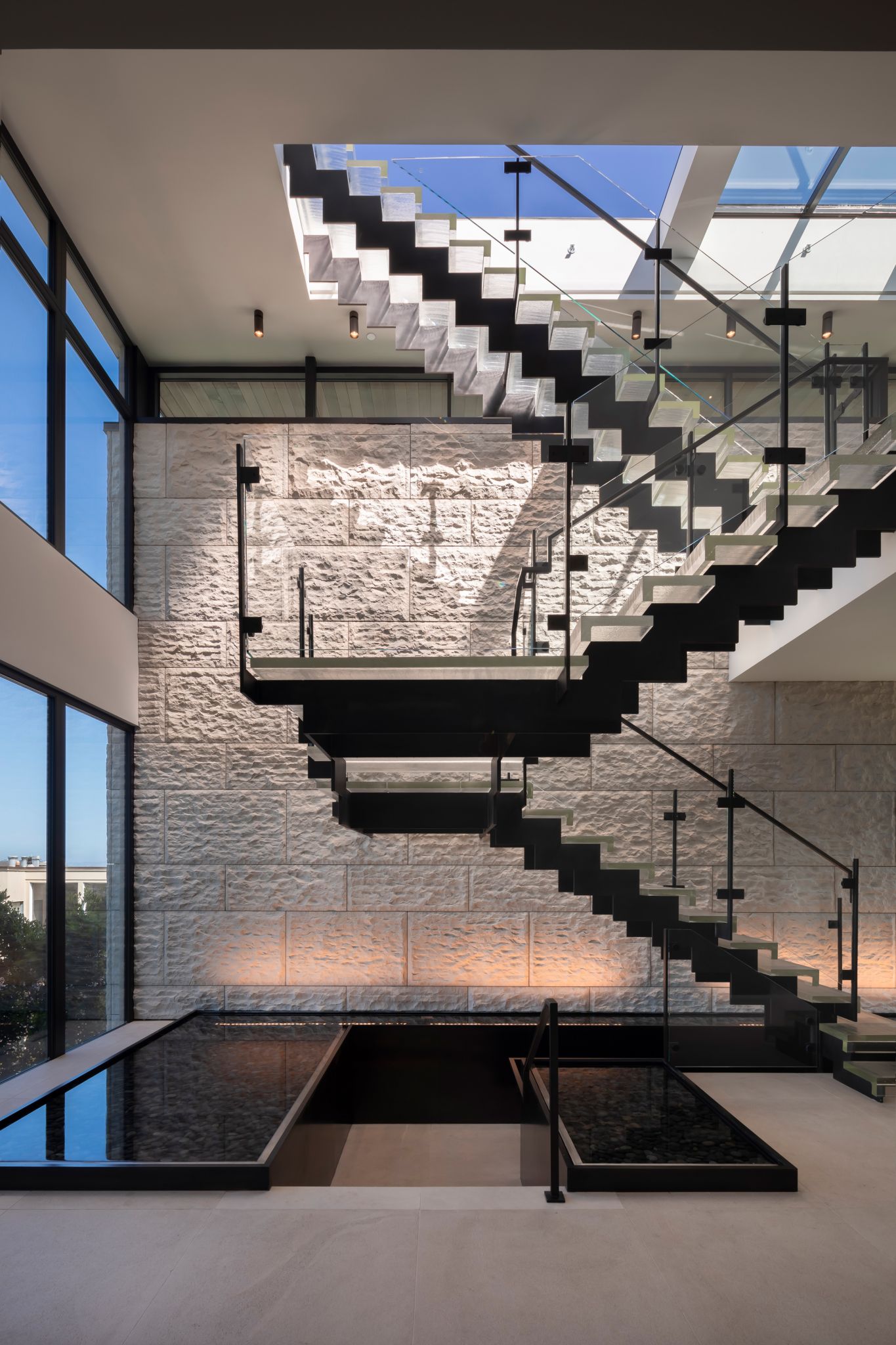 The home has a high-speed elevator, but this floating glass staircase, rising up over indoor reflecting pools toward a massive operable skylight, is art. 