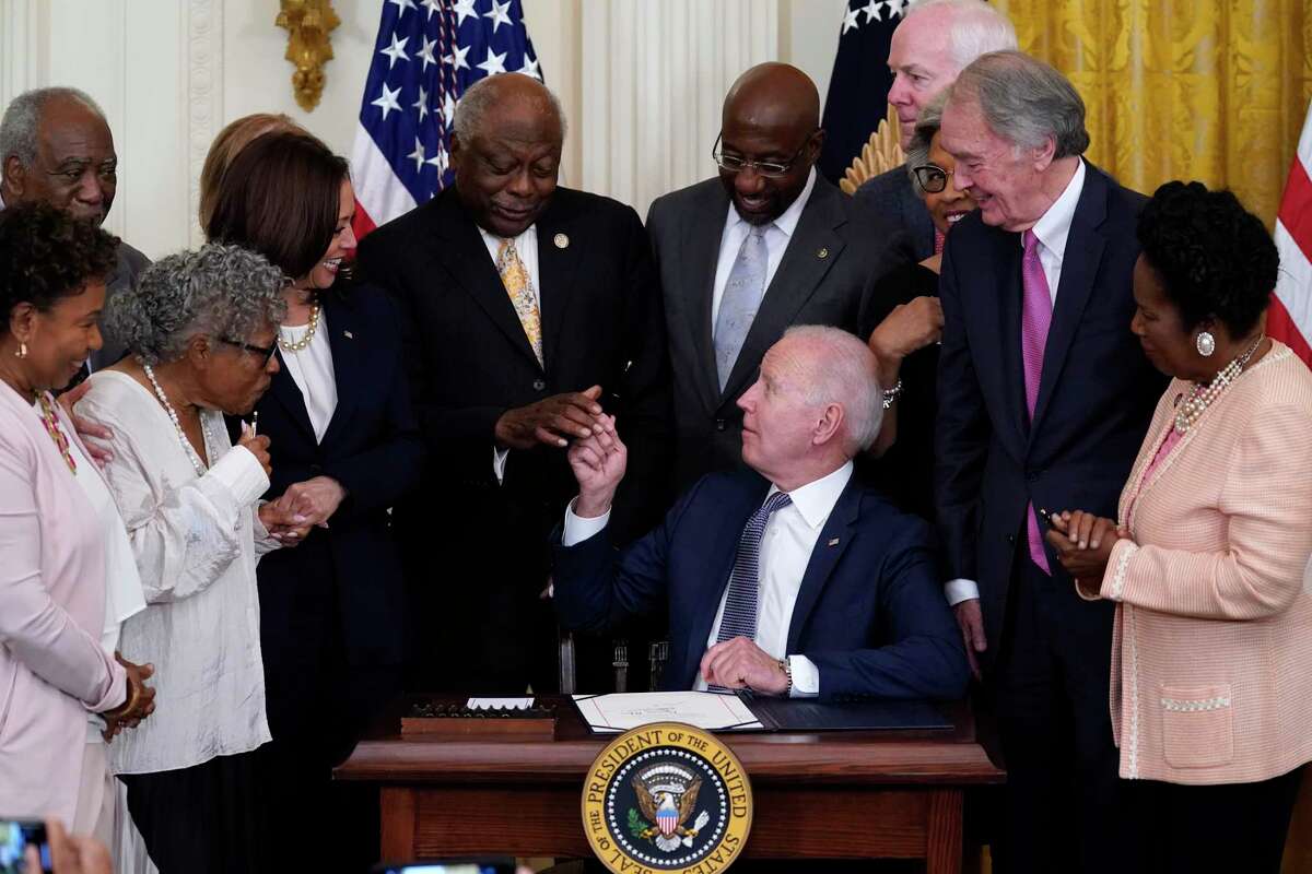 President Joe Biden hands a pen to House Majority Whip James Clyburn of S.C., after signing the Juneteenth National Independence Day Act, in the East Room of the White House, Thursday, June 17, 2021, in Washington. From left, Rep. Barbara Lee, D-Calif, Rep. Danny Davis, D-Ill., Opal Lee, Sen. Tina Smith, D-Minn., obscured, Vice President Kamala Harris, Clyburn, Sen. Raphael Warnock, D-Ga., Sen. John Cornyn, R-Texas, Rep. Joyce Beatty, D-Ohio, obscured, Sen. Ed Markey, D-Mass., and Rep. Sheila Jackson Lee, D-Texas.