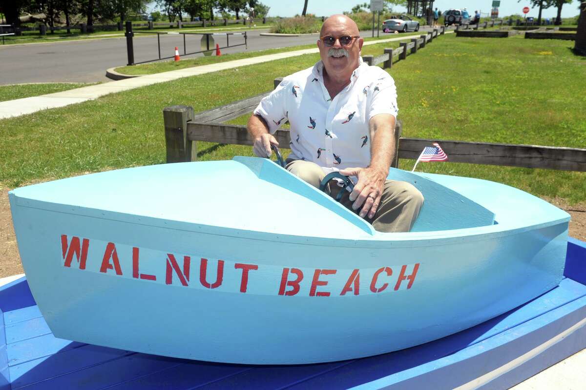 Max Nowicki sits in one of the old boats he and his family have saved from a ride at the former Walnut Beach Amusement Park, in Milford, Conn. June 17, 2021. Nowicki recently refurbished a couple of the boats, which are now on display at Walnut Beach.