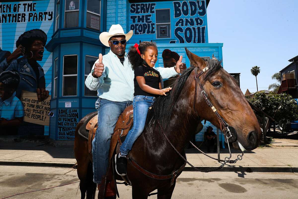 Donnell McAlister of Vallejo gives a thumbs-up as Dakota Lane, 6, of San Pablo pets his horse JJ during Oakland’s Juneteenth celebration.