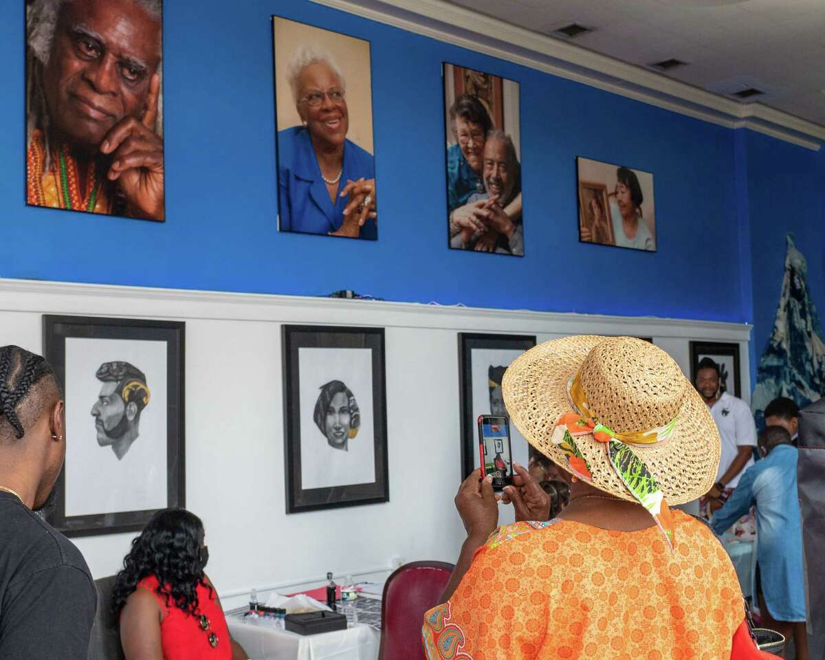 Vet Cowan takes photos of artwork hanging on the walls of the African American Cultural Center of the Capital Region in Albany, NY, during the Juneteenth celebration commemorating the end of slavery in the U.S. on Saturday, June 19, 2021 (Jim Franco/Special to the Times Union)
