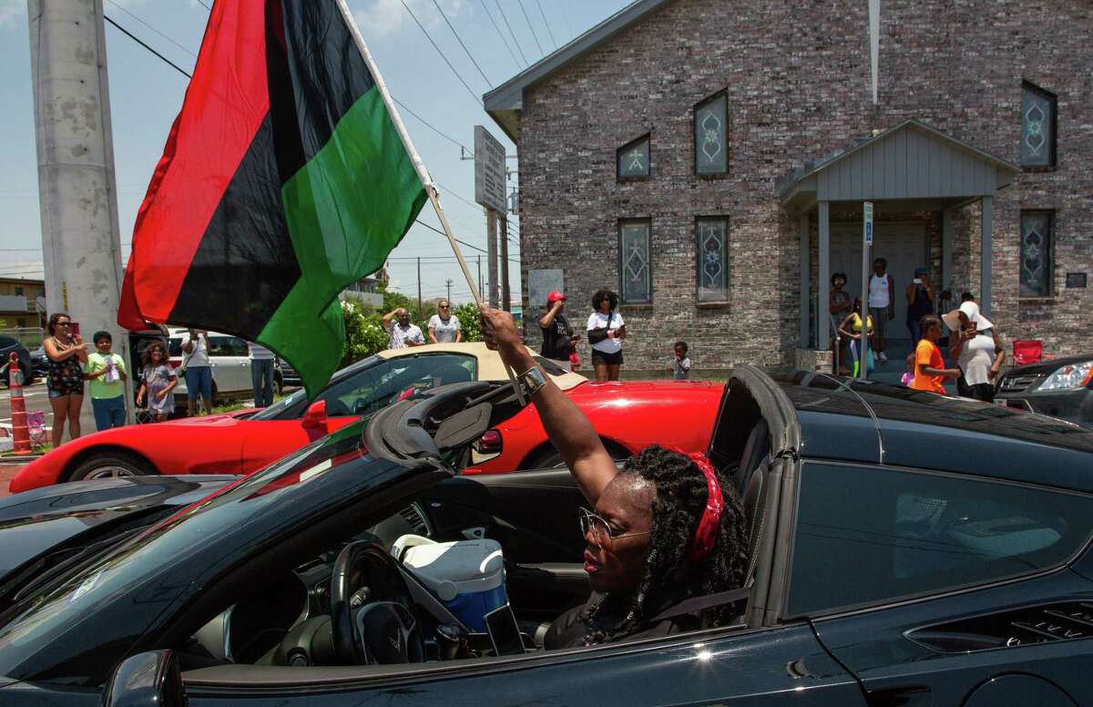 Savannah Taplin waves a Black Liberation flag while participating in the Juneteenth Parade on Ball Street on June 19, 2021, in Galveston.
