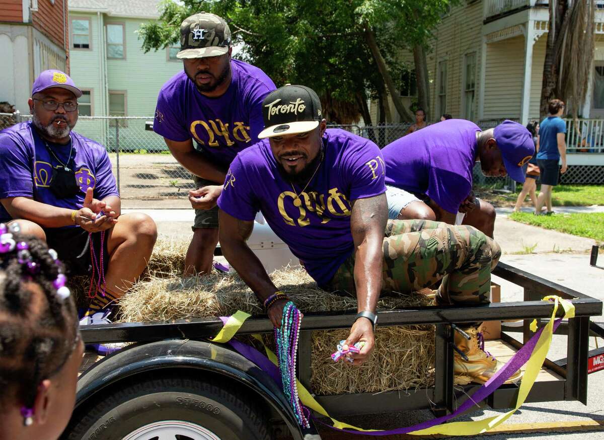Members of the Omega Psi Phi fraternity hand out candy to children during the Juneteenth Parade on Ball Street on June 19, 2021, in Galveston.