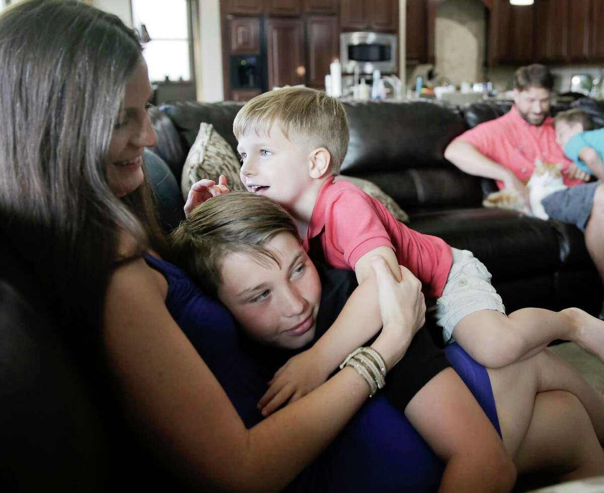 Ann Marie Timmerman's sons Tim, 11, and Tristan, 3, pile on her as her husband, Tim and son Peyton, play in the background in their Cinco Ranch, Texas home on Tuesday, June 18, 2019.