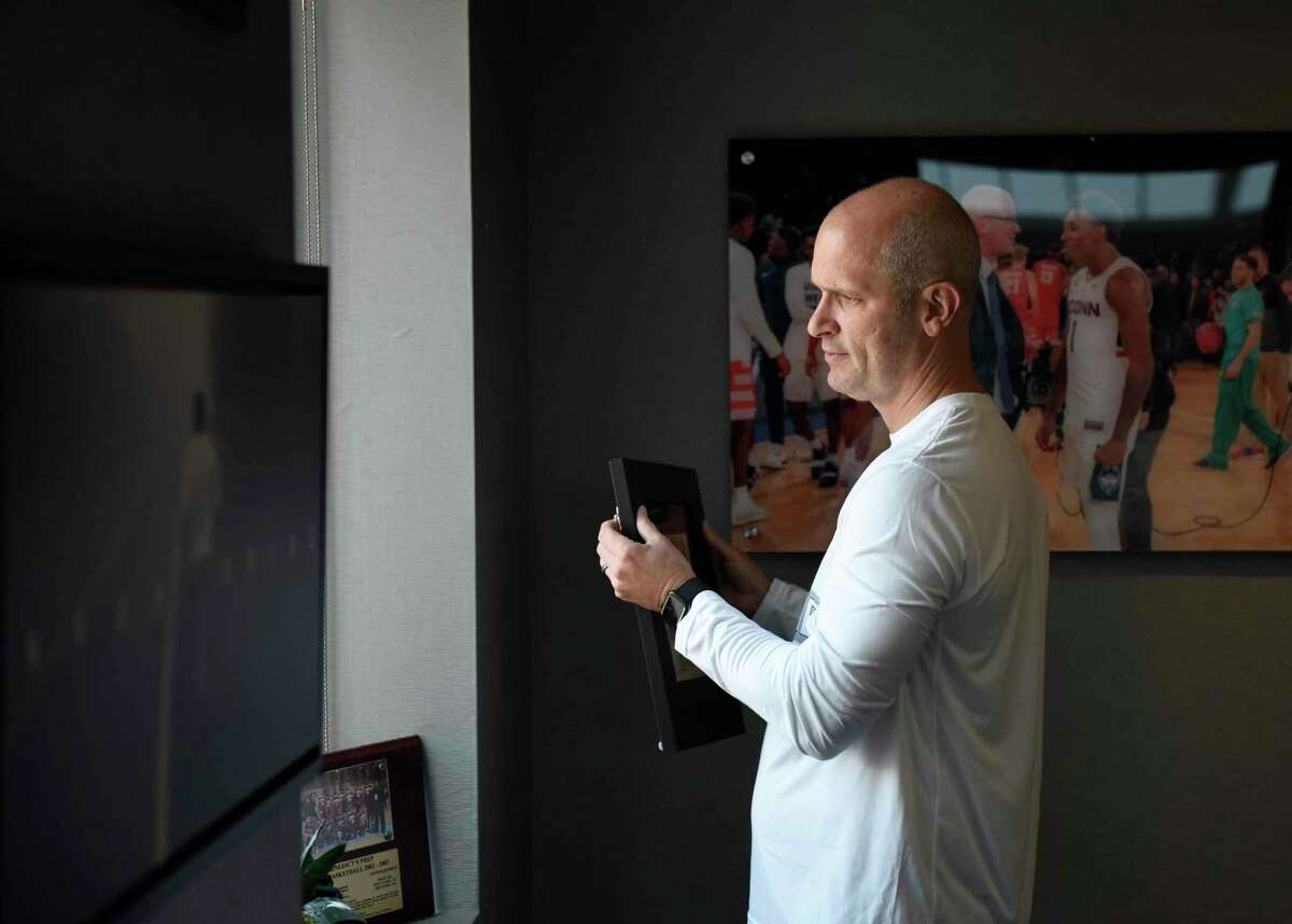 UConn men's basketball coach Dan Hurley takes a framed photo off the wall in his office before practice at the Werth Family UConn Basketball Champions Center on the UConn main campus in Storrs, Conn. Wednesday, June 9, 2021.