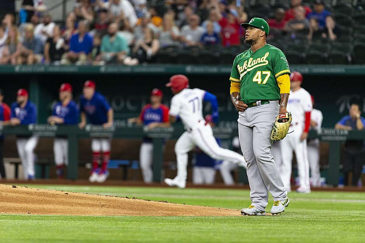 Oakland Athletics pitcher Frankie Montas, center, hands the ball