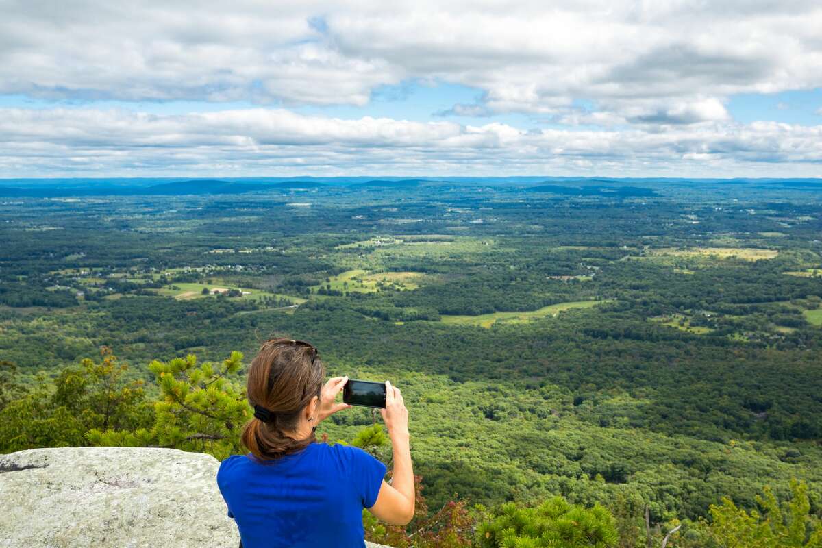 A woman takes a photo during a hike of Gertrude's Nose Trail in Minnewaska State Preserve Park in the Hudson Valley. During the pandemic, the region experienced a surge in visitors and transplants from New York City. Will that tourism trend continue?