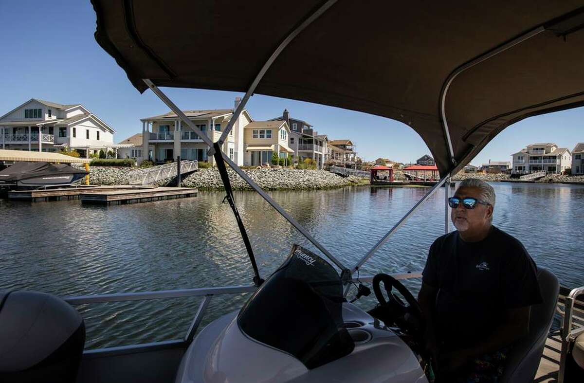 Michael Temby, Community Ambassador at Delta Coves, cruises past homes in Bethel Island.