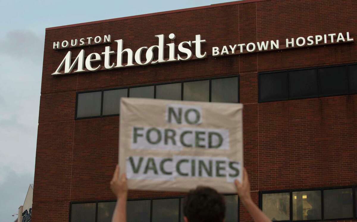 FILE - In this June 7, 2021, file photo, a person holds a sign to protest at Houston Methodist Hospital in Baytown, Texas, a policy that says hospital employees must get vaccinated against COVID-19 or lose their jobs. A federal judge dismissed their lawsuit, saying if workers don’t like the rule, they can go find another job. (Yi-Chin Lee/Houston Chronicle via AP, File)