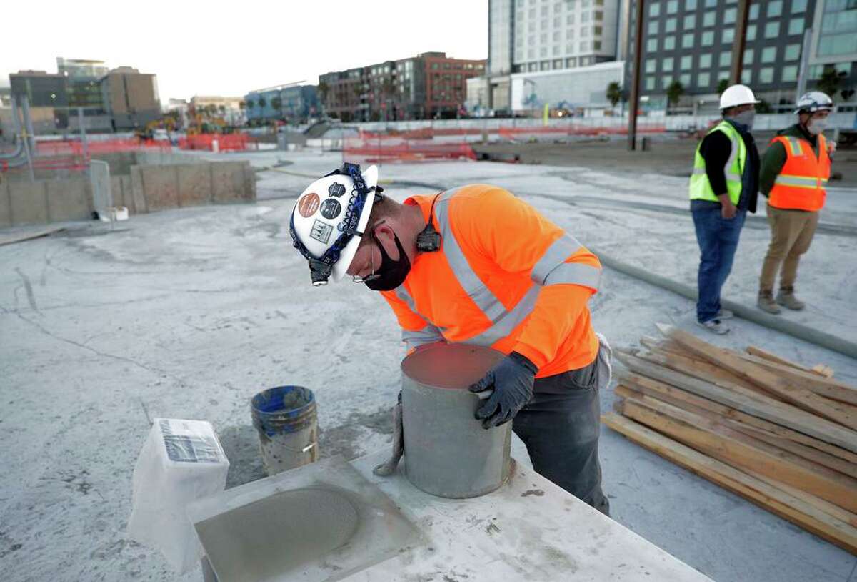 A construction worker with Cell-crete measures the weight of a bucket of lightweight cellular concrete as the company pours in a section of the new Mission Rock development near Oracle Park.