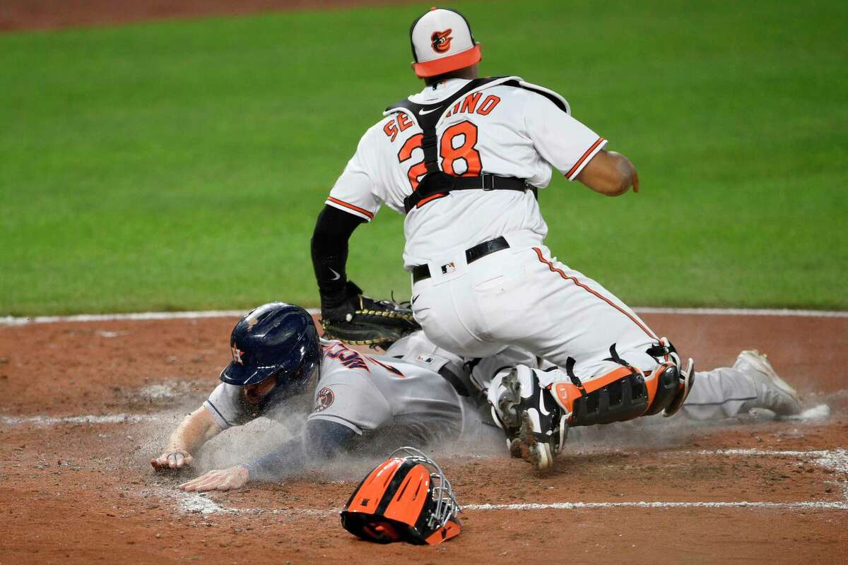 Houston Astros' Chas McCormick, left, slides home to score on a single by Myles Straw during the seventh inning of a baseball game, Tuesday, June 22, 2021, in Baltimore. Baltimore Orioles catcher Pedro Severino is at right. (AP Photo/Nick Wass)
