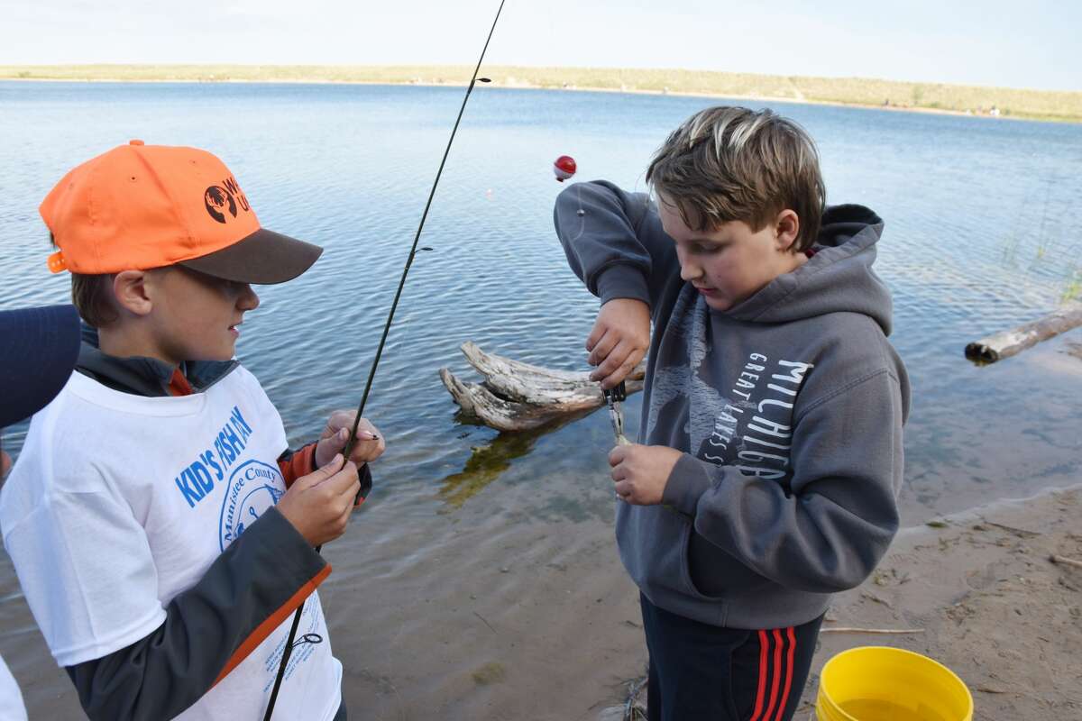 Richard Kamaloski (right) helps Nolan Koscinski to remove a hook from a fish at Man Made Lake on Wednesday.