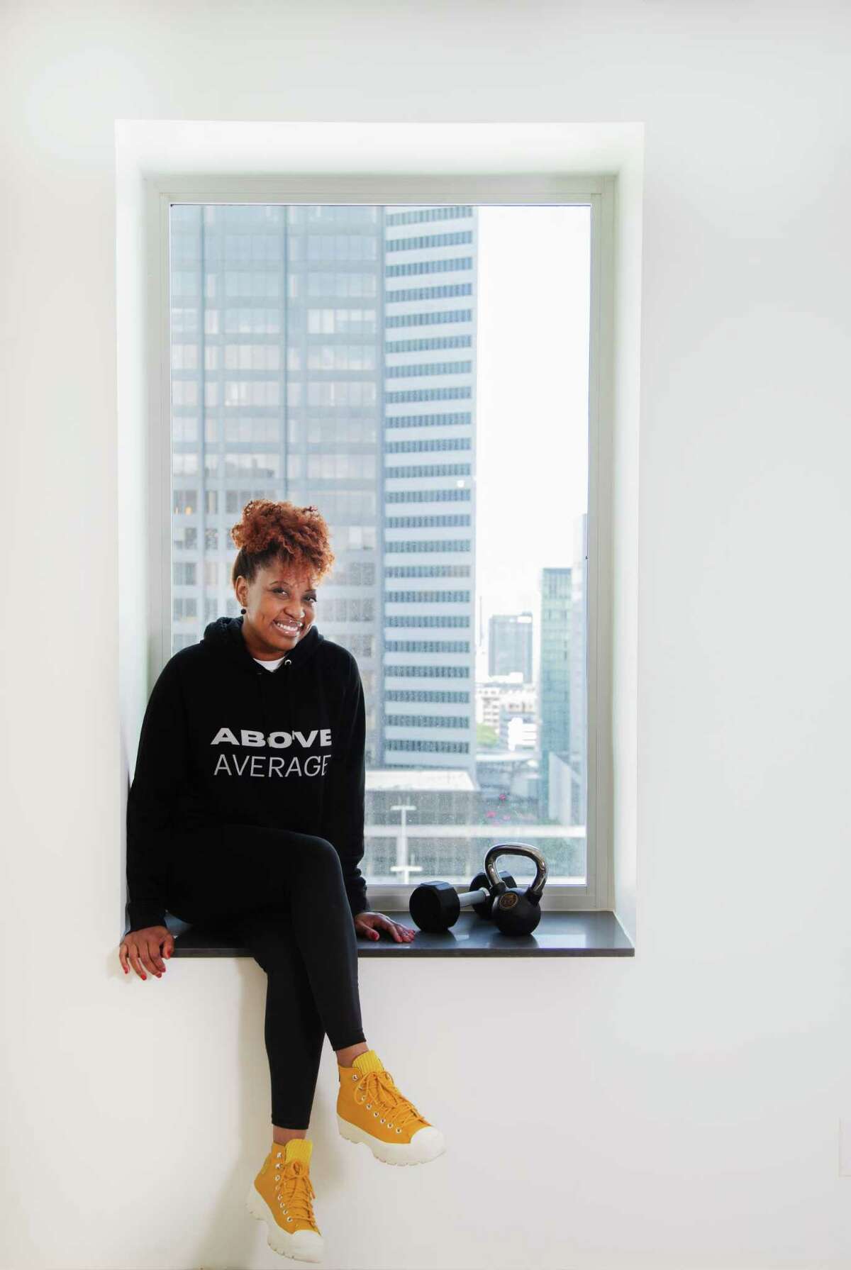 Dawn Callahan models one of the athletic sportswear hoodies she created with the message “Above Average,” Monday, May 10, 2021, in Houston. Callahan created the clothing during the pandemic as her side project.