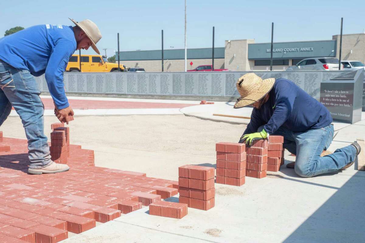 Work continued in June on the Veteran's Memorial in front of the Midland County Annex as Diego Lozano places bricks as Gabriel Garcia brings stacks of bricks as they and others with Lawn and Tree Tech, LLC work on the pathways in front of the memorial. Tim Fischer/Reporter-Telegram