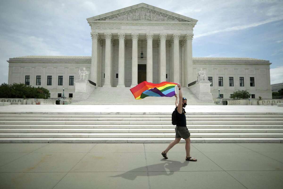 Joseph Fons holds a Pride flag as he walks back and forth in front of the U.S. Supreme Court building last June after the court ruled that LGBTQ people can not be disciplined or fired based on their sexual orientation.