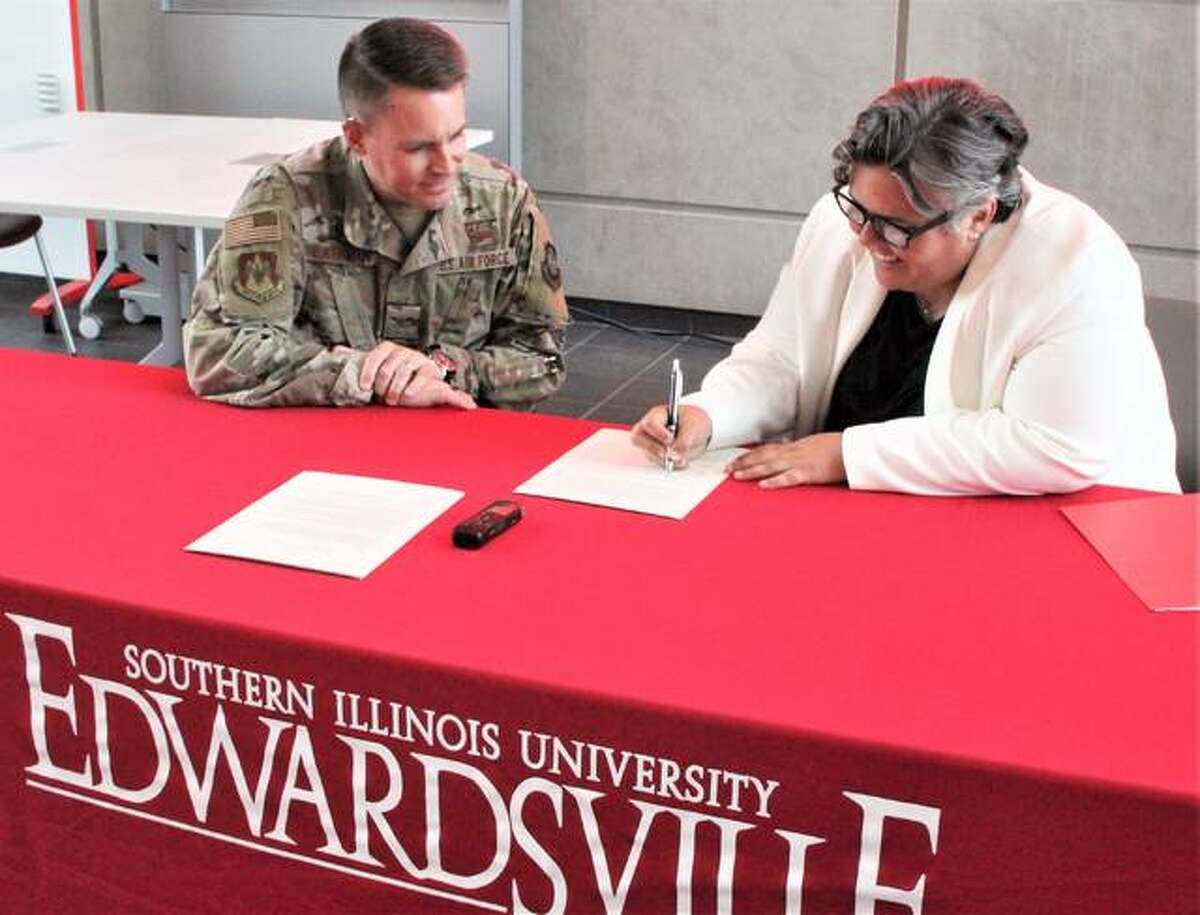 Col. J. Scot Heathman, commander of the 375th Air Mobility Wing at Scott Air Force Base, in Belleville, watches as Southern Illinois University Edwardsville Provost and Vice Chancellor for Academic Affairs Denise Cobb signs a three-year educational agreement between the university and the unit’s “innovation hub” called Elevate. The agreement is designed to allow a formal exchange of expertise and resources between the base and university.