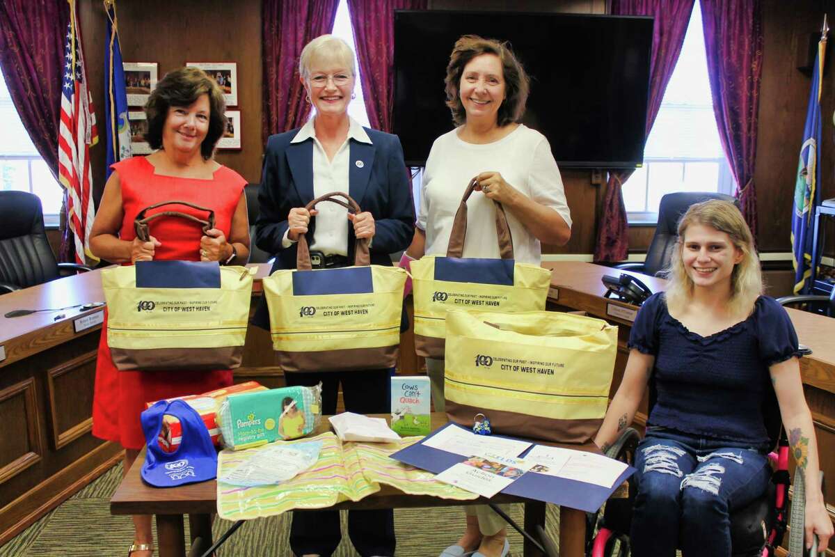 From left, City Clerk Patricia C. Horvath, Mayor Nancy R. Rossi and West Haven Child Development Center Executive Director Patrice Farquharson, with daughter Julia Farquharson, 22, reveal West Haven’s new centennial diaper bags at City Hall on June 23. The yellow-and-brown bags, which contain provisions for parents of newborns, were made possible by the Child Development Center and the West Haven Community House through a donation from the Eder family.