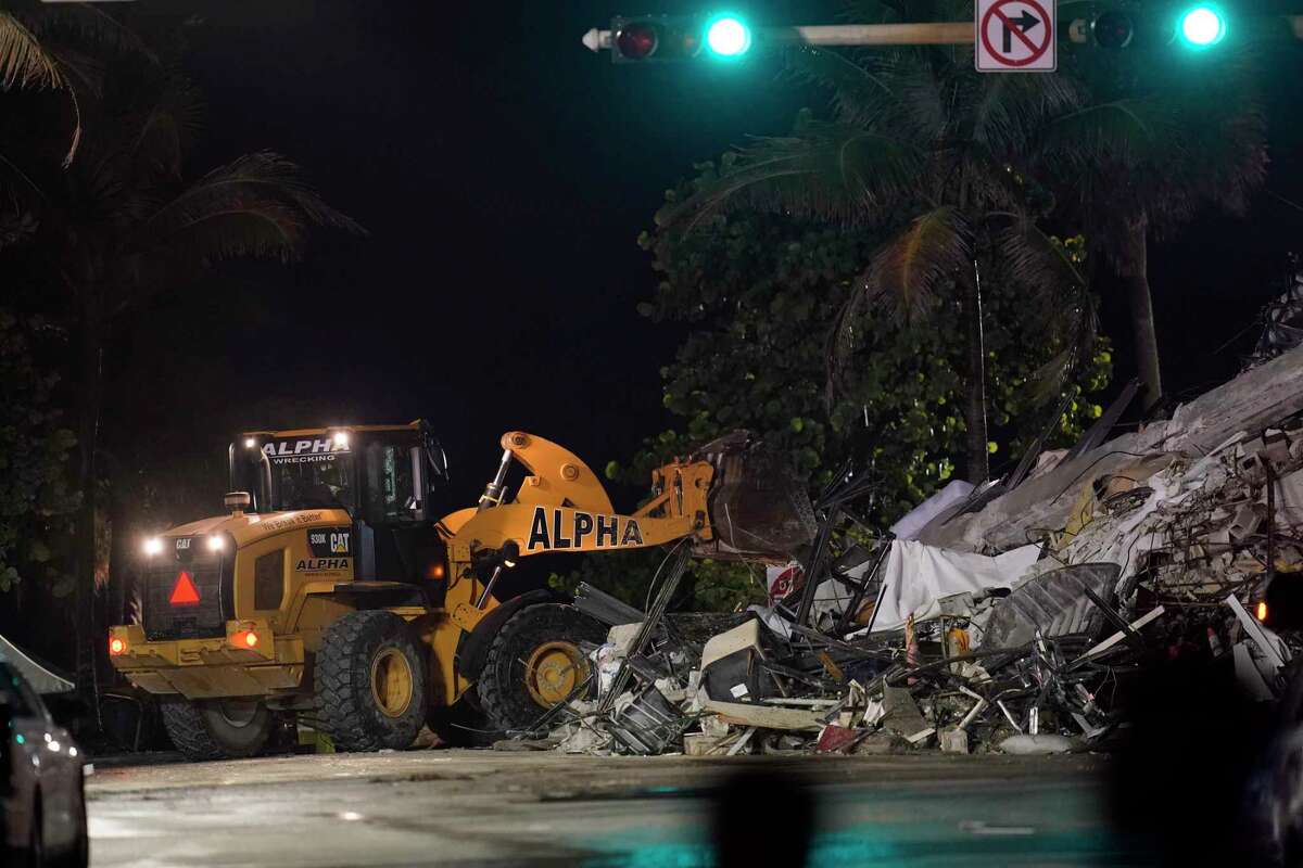 A front end loader shifts rubble mixed with furniture and household items, as rescue efforts continue where a wing of a 12-story beachfront condo building collapsed, late on Thursday, June 24, 2021, in the Surfside area of Miami.