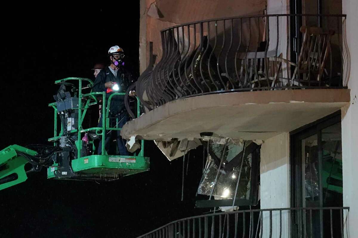 Workers use a lift to investigate balconies in the still-standing portion of the building adjacent to where a wing of a 12-story beachfront condo building collapsed, late on Thursday, June 24, 2021, in the Surfside area of Miami.