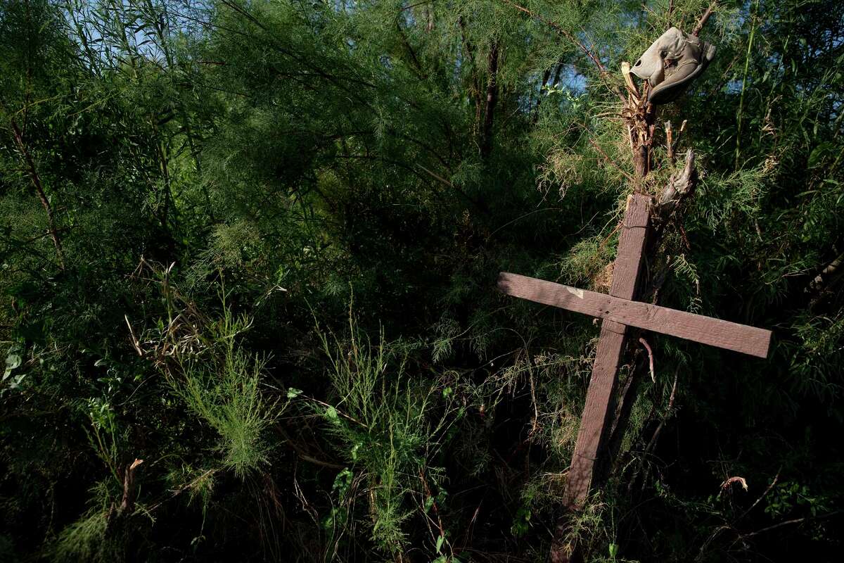 In a clearing on the Mexican side of the dry Rio Grande, a handmade cross with a tattered shoe sits in the bushes.