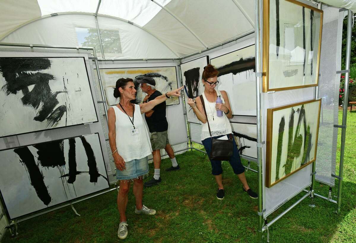 Artist Audrey Klotz points out her work to Tony and Mary Scimone during The Norwalk Art Festival Saturday, June 26, 2021, at Mathews Park in Norwalk, Conn. The festival which continues Sunday features the works of 100 juried artists exhibiting a wide variety of media including, photography, drawing, ceramics, jewelry, painting, mixed media, printmaking, fiber, metal sculpture and glass. The Center for Contemporary Printmaking, Stepping Stones Museum, Mathews Mansion Museum and The Norwalk Parks Department, sponsored the festival.