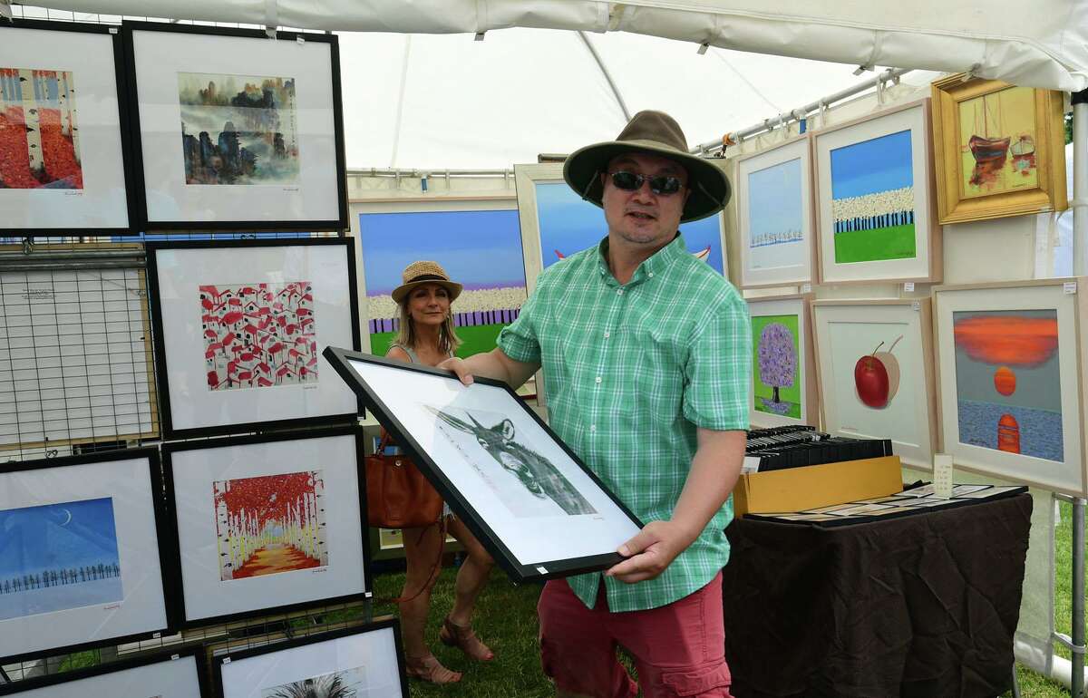 Aitist Simon Weng shows of his prints during the Norwalk Art Festival on Saturday.