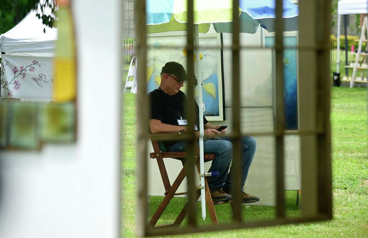 Painter David Gordon stays out of the sun during The Norwalk Art Festival Saturday, June 26, 2021, at Mathews Park in Norwalk, Conn. The festival which continues Sunday features the works of 100 juried artists exhibiting a wide variety of media including, photography, drawing, ceramics, jewelry, painting, mixed media, printmaking, fiber, metal sculpture and glass. The Center for Contemporary Printmaking, Stepping Stones Museum, Mathews Mansion Museum and The Norwalk Parks Department, sponsored the festival.
