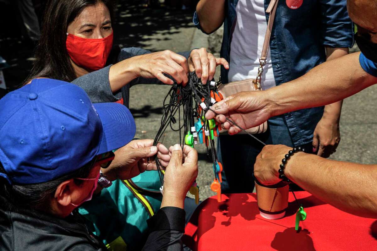 Volunteers untangle a bundle of whistles during the AAPI Care Fair at Portsmouth Square in Chinatown's Portsmouth Square in San Francisco, Calif. Saturday, June 26, 2021.