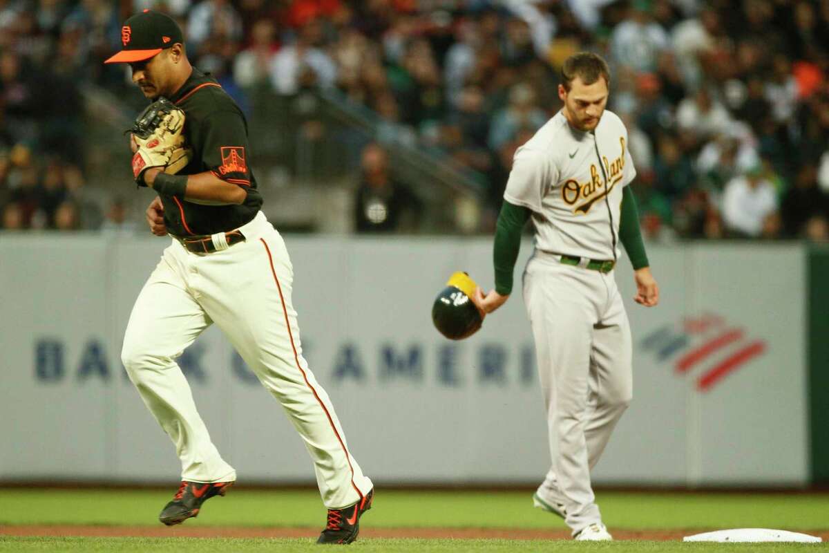 San Francisco Giants second baseman Donovan Solano jogs back to the dugout after his throw to first gets Oakland Athletics second baseman Tony Kemp (5) out to end the top of the fourth inning during an MLB game at Oracle Park, Saturday, June 26, 2021, in San Francisco, Calif. Oakland Athletics Chad Pinder (4), who ran to second base during the groundout, reacts to the end of the inning.