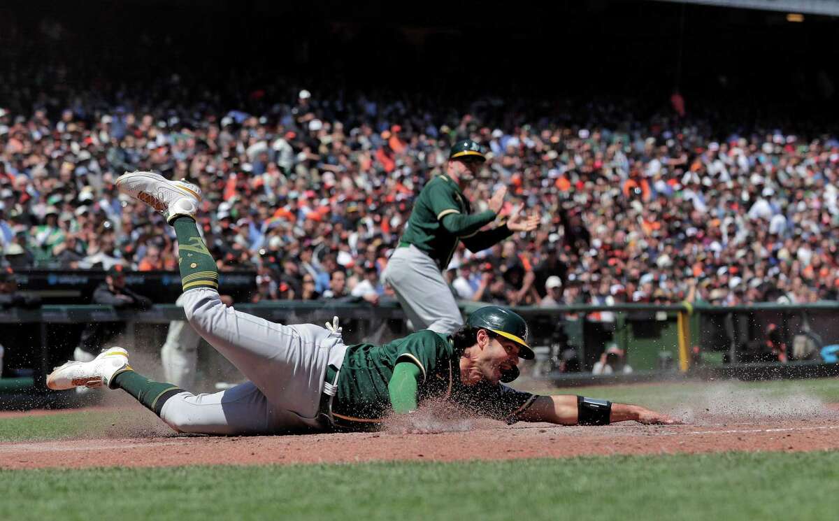 Aramis Garcia (37) reaches back to tag the plat to score on a hit by Elvis Andrus (17) in the sixzth inning as the San Francisco Giants played the Oakland Athletics at Oracle Park in San Francisco, Calif., on Sunday, June 27, 2021.