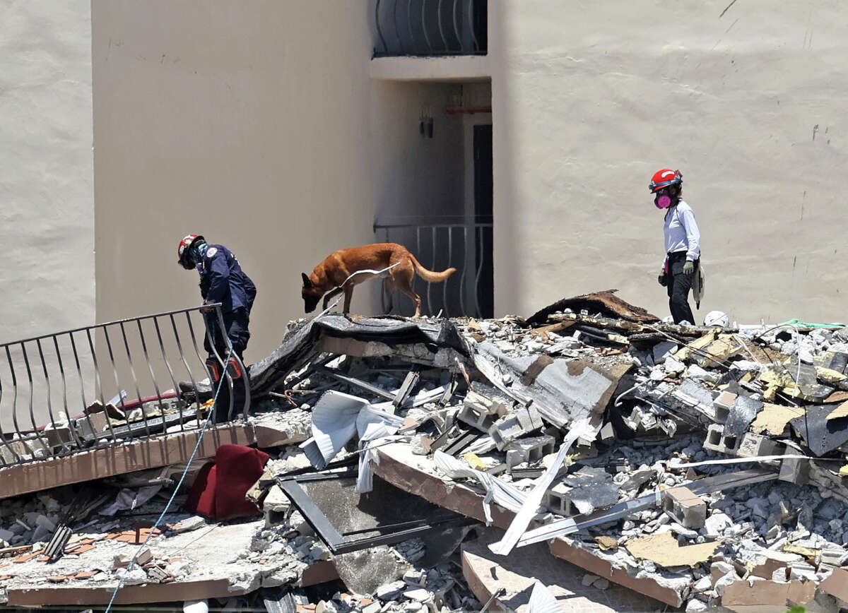 Search and rescue personnel search for survivors through the rubble with their dogs at the Champlain Towers South in Surfside, Fla., Sunday, June 27, 2021. The apartment building partially collapsed on Thursday, June 24. (David Santiago/Miami Herald via AP)