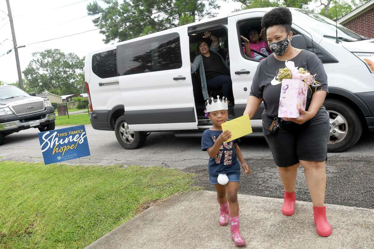 Tonya Castille and granddaughter Kaze Sullivan collect cards and gifts for Diverna Abatte during a drive-by parade and celebration at her home to honor her 42 years serving as a foster parent. Abatte fostered with Buckner since 2002, but began her lifelong ministry of fostering with Jefferson County's Child Protective Services in 1979. In all, roughly 175 children have crossed her doorstep throughout the years, many. of which she has kept up with over the years. Photo made Wednesday, June 23, 2021 Kim Brent/The Enterprise