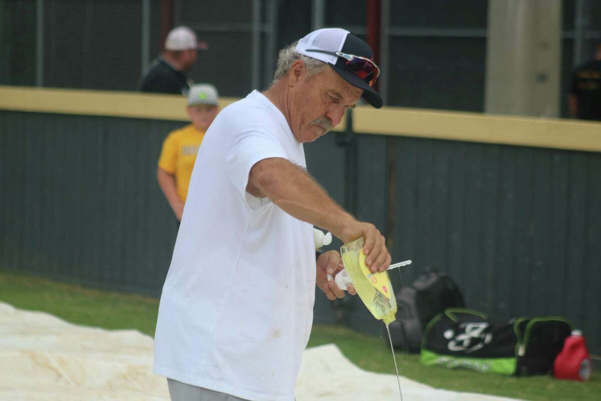 Deer Park High School head baseball coach Chris Rupp pours liquid soap onto a large sheet, preparing his campers for fun with a slip-and-slide.